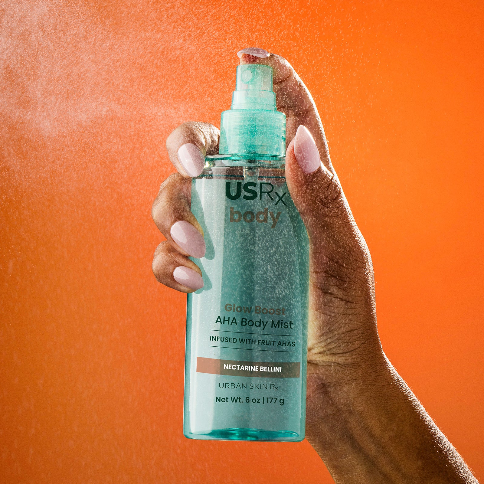Woman spraying a mist from bottle of USRx Glow Boost AHA Body Mist in Nectarine Bellini