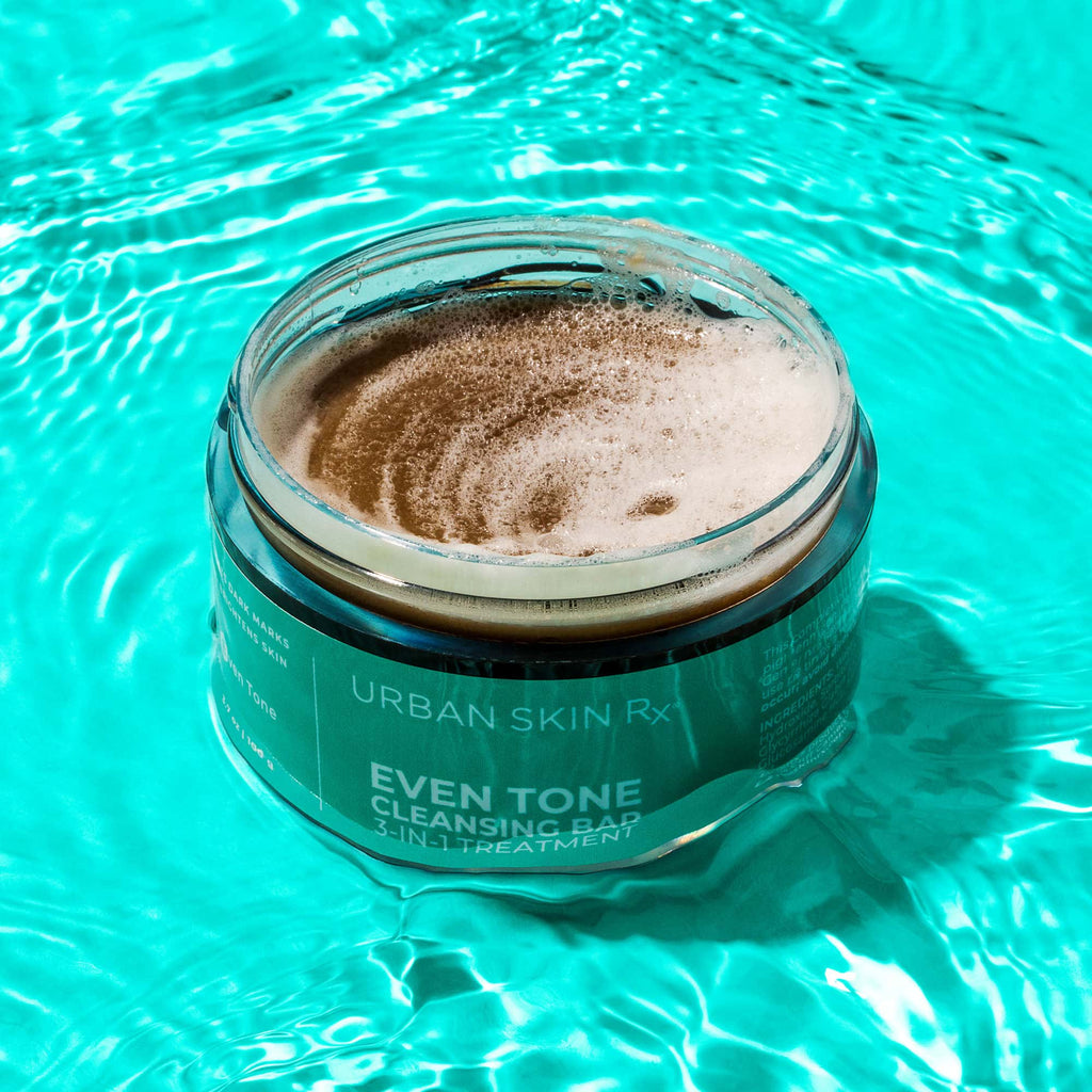 Open jar of USRx Even Tone Cleansing Bar on a blue background