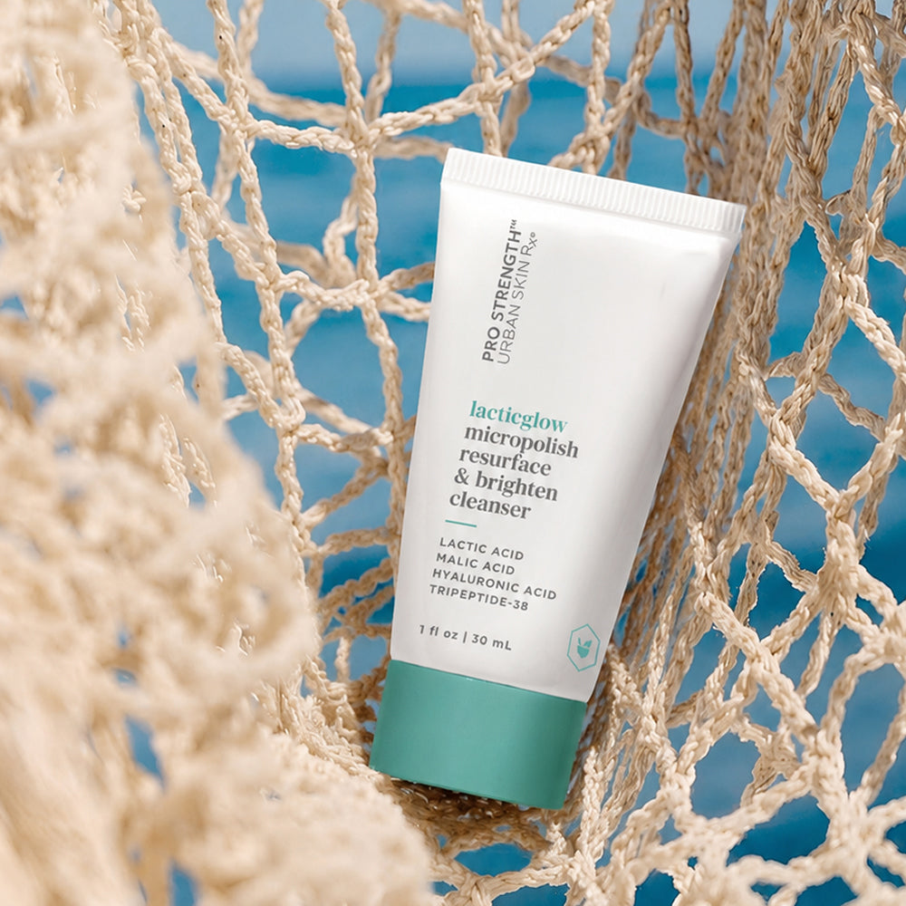 Mini bottle of USRx LacticGlow Cleanser on a net on a blue background