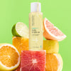 Bottle of USRX Super C Body Bright Oil with an assortment of citrus fruit around