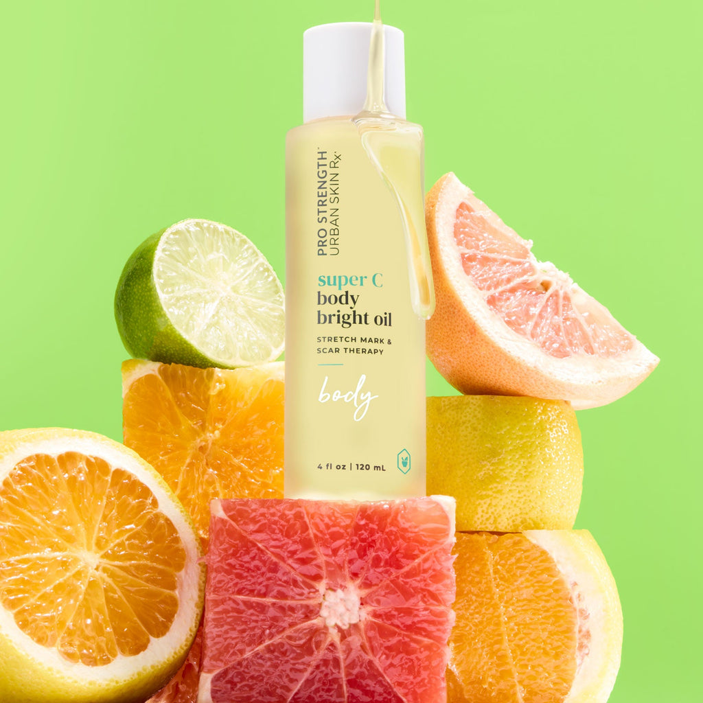 Bottle of USRX Super C Body Bright Oil with an assortment of citrus fruit around