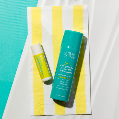 Duo of Urban Skin RX Sunscreen Lip Balm and Complexion Protection Moisturizer Sunscreen SPF30 set against yellow striped beach towel