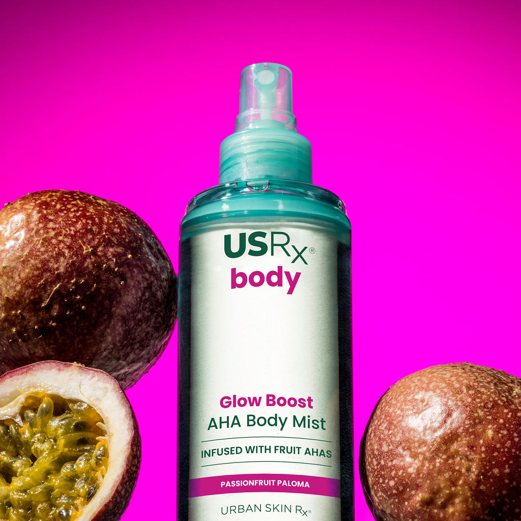 Bottle of USRX Glow Boost AHA Body Mist in Passionfruit Paloma next to tropical fruits