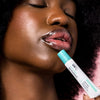 Woman holding USRx Hydrating Lip Treatment in Original next to her glossy lips