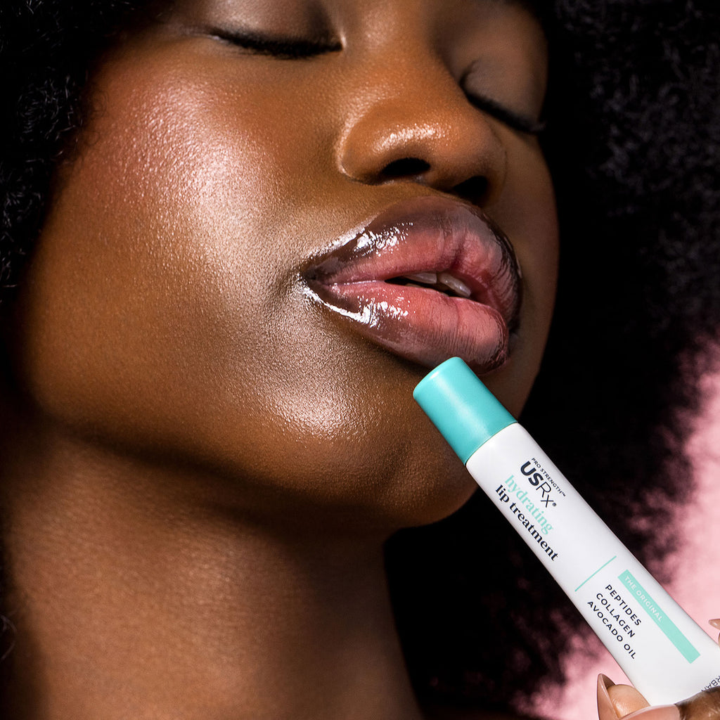Woman holding USRx Hydrating Lip Treatment in Original next to her glossy lips