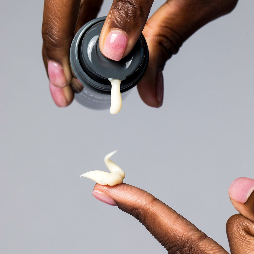 Woman dispensing a drop of USRx Fade Fix Serum onto her finger