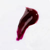 Swatch of deep plum, glossy USRx Tinted Hydrating Lip Treatment in Juicy on a white background