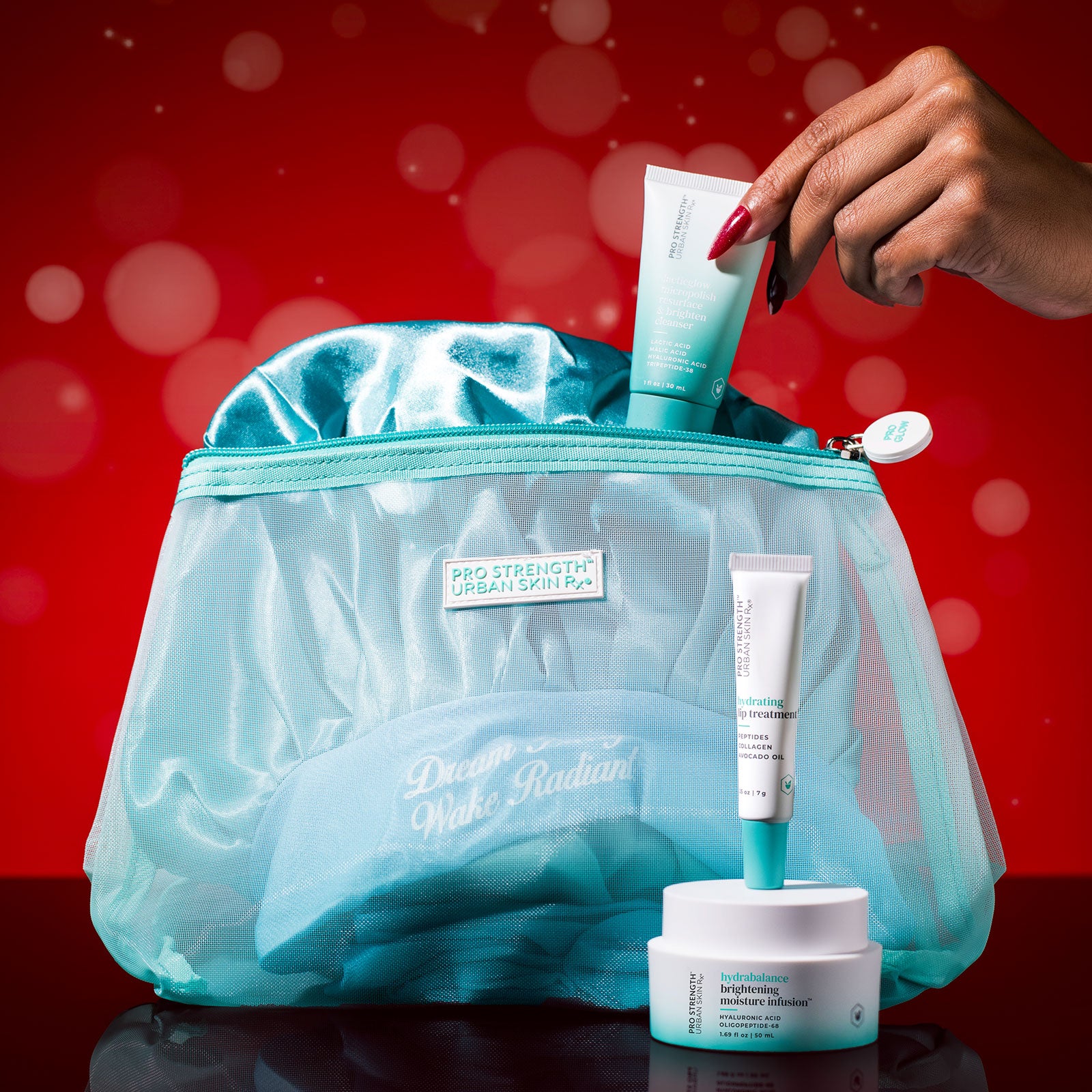 USRx Pro Strength Holiday Kit including USRx Lacticglow Cleanser, Hydrabalance Brightening Moisture Infusion, and Hydrating Lip Treatment with a Satin bonnet and branded travel bag on a red background