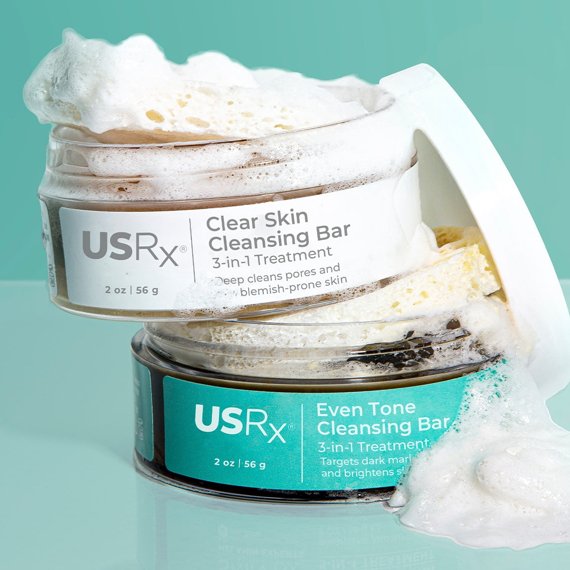 Two open jars of USRx Cleansing Bars with suds coming out of the jars against a light blue background