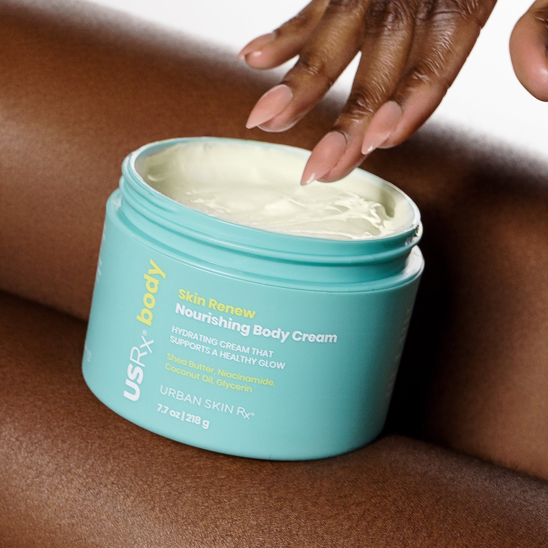 Woman scooping product from open jar of USRx Skin Renew Nourishing Body Cream