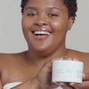 Woman opening jar of Urban Skin RX Clear and Even Tone Body Cleansing Bar and using sponge to apply product on skin